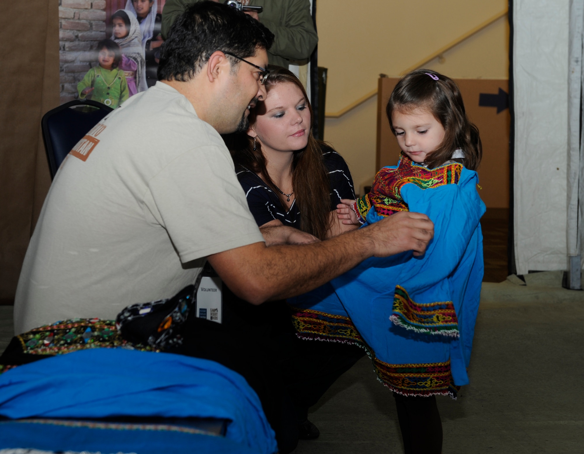 Ambassador Wahid Monawar, Camp Desert Kids volunteer, assists Nicole Mixon dress her three-year-old daughter, Abby, in traditional Afghanistan clothing during the CDK’s visit to Mountain Home Air Force Base, Idaho, Oct. 15, 2011. More than 50 children got a glimpse into deployment life during this the event, which also marked the first time the CDK has visited an Air Force base.  (U.S. Air Force photo by Senior Airman Angelina Drake)  