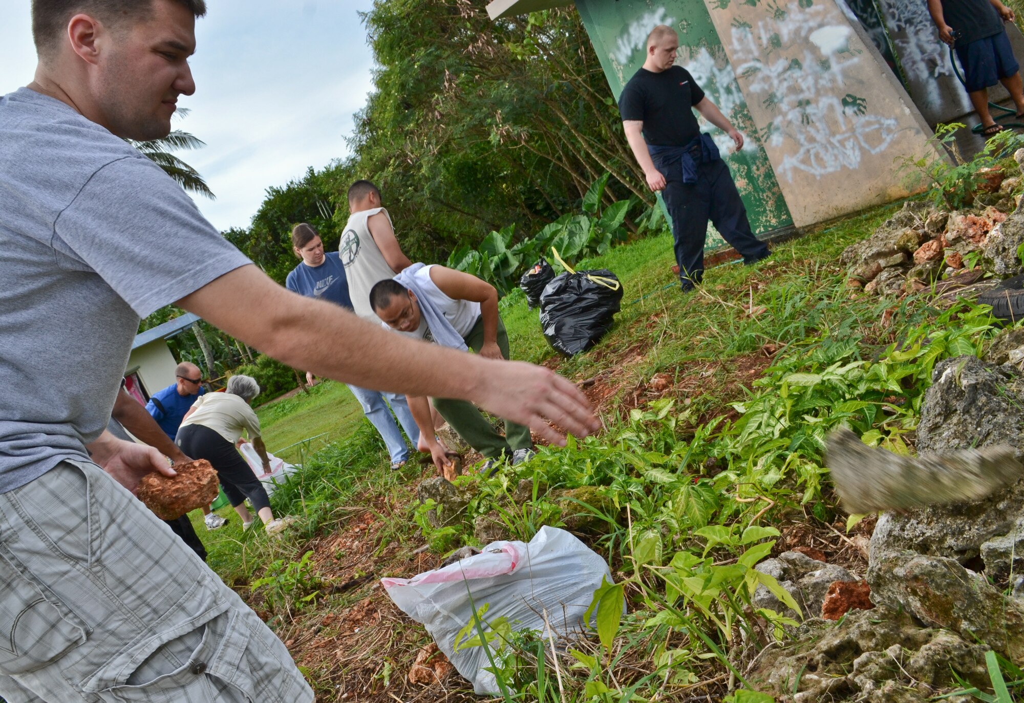 Airmen from the 36th Maintenance Squadron, 36th Wing chapel and their families pick up debris and trash prior to painting a bus stop for an Island Beautification project in Mangilao, Guam Oct 15.  Throughout the year, squadrons from Andersen AFB volunteer their time to help clean, repair and build areas in Guam communities in support of the Islandwide Beautification Task Force. (U.S. Air Force photo by Staff Sgt. Alexandre Montes/RELEASED) 