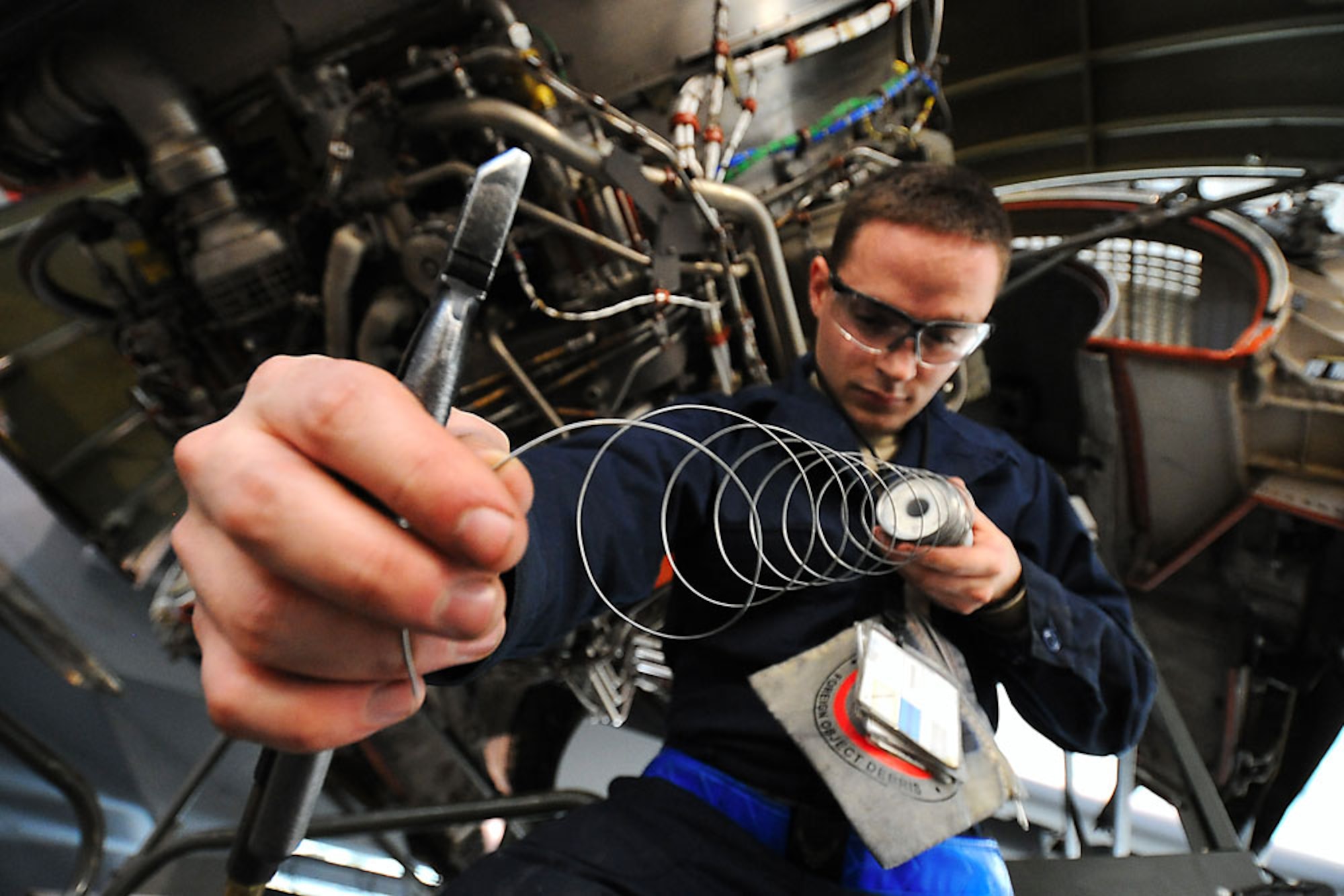 Airman 1st Class Jared Henson stretches safety wire just before cutting it for use during a home station check, Oct. 11. The intense, four-day inspection of the C-17 Globemaster III checks the ins and outs of the aircraft, not a part of a normal everyday inspection.  Henson is an aerospace propulsion specialist with the 3rd Maintenance Squadron. (U.S. Air Force photo/Senior Airman Cynthia Spalding)