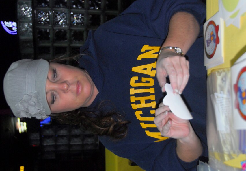 Lori White applies stickers to plastic bags on the "Cookie Crunch" assembly line Oct. 20, 2011.  White, fiancé of Staff Sgt. Matt Musick, was one of 15 volunteers on the afternoon shift who built bags of cookies for delivery to more than 9,000 unaccompanied military people stationed all over the Korean peninsula.  "Cookie Crunch" is a holiday cheer project of the Osan Air Base Officer Spouses Club.  (Air Force photo by Senior Master Sgt. Stuart Camp)