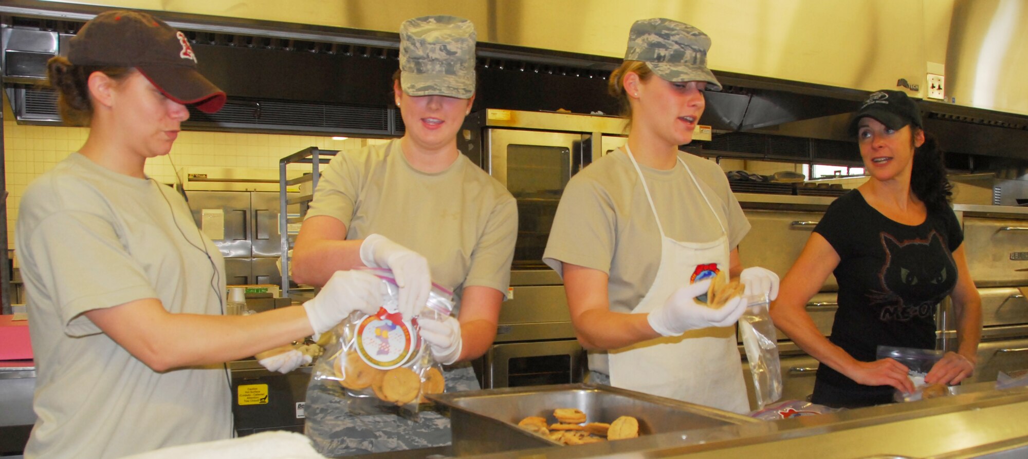 Staff Sgt. Paula Howell and Senior Airman Isabella McKay, 51st Communications Squadron; Airman 1st Class Rachel Bogard, 303rd Intelligence Squadron; and Lisa Kennelly, spouse of Lt. Col. Kevin Kennelley, 51st Operations Group; form an assembly line Oct. 20, 2011, for "Cookie Crunch" bags. Two shifts of 15 volunteers met several days this week at the Mustang Club to bake and bag more than 10,000 cookies a day. The goal of the Osan Air Base Officer Spouses Club is to deliver more than 76,000 cookies to military people who are on assignment to Korea during the 2011 holiday season.  (Air Force photo by Senior Master Sgt. Stuart Camp)