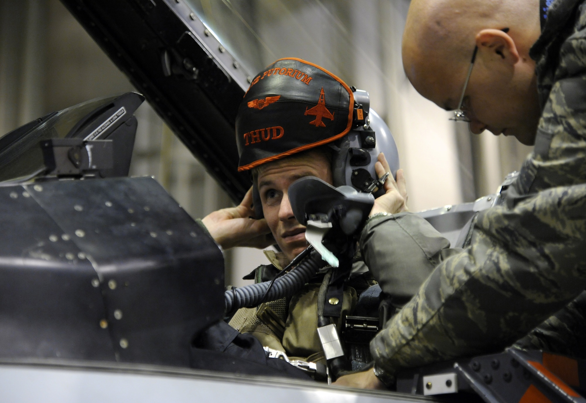 U.S. Air Force Captain Chris Behrens puts his helmet on as Senior Airman Matthew Smith secures him in the jet Oct. 12, 2011, Eielson Air Force Base, Alaska. Behrens is participating in RED FLAG-Alaska, where he plays the role as a coalition aircraft defending against mock aggressors. Behrens is an F-16 Fighting Falcon pilot assigned to the 13th Fighter Squadron, Misawa Air Base, Japan. Smith is a crew chief assigned to the 35th Aircraft Maintenance Squadron, Misawa Air Base, Japan. (U.S. Air Force photo by Senior Airman Willard E. Grande II/Released)