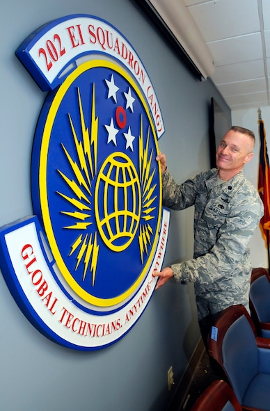 Lt. Col William "Bill" Lipko, 202nd EIS detachment commander, shows where he plans to hang the unit logo in the new multi purpose training room. U. S. Air Force photo by Sue Sapp