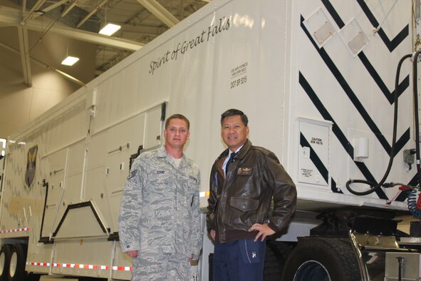 Col. H.B. Brual, 341st Missile Wing commander, paid a visit to Staff Sgt. Michael Adams, 341st Missile Maintenance Squadron MMT technician, after he completed his 100th safe trip in a payload transporter van, picture behind them. He is one of eight technicians to have accomplished this noteworthy task. (U.S. Air Force Courtesy Photo)