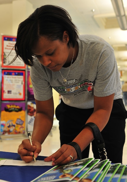 Michelle, wife of U.S. Air Force Airman 1st Class Joshua Jaynes, 41st Rescue Squadron crew chief, fills out a raffle slip for an energy conservation kit while visiting the Energy Conservation Month booth in the Exchange on Moody Air Force Base, Ga., Oct. 18, 2011. The conservation kit is filled with compact florescent light bulbs, a showerhead, toilet tank bank, foam gaskets for electrical outlets and various other energy-efficient items. (U.S. Air Force photo by Staff Sgt. Stephanie Mancha/Released)