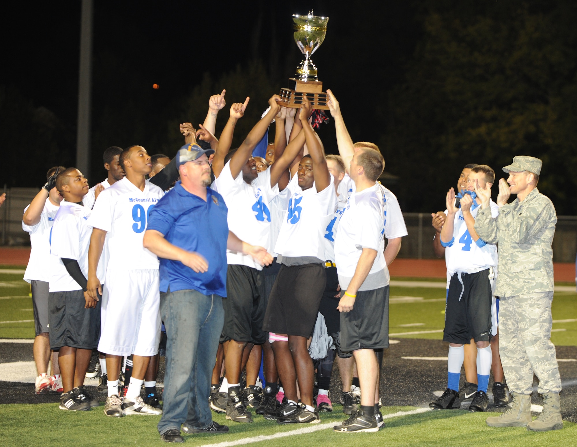The McConnell Tornadoes lift the traveling trophy to celebrate their victory over Fort Riley’s Team after the annual flag football game at Panther Field, Oct. 15, 2011, Derby, Kan.  The Tornadoes beat Fort Riley despite going into the fourth quarter with a zero score.  (U.S. Air Force/Airman 1st Class Jose L. Leon)