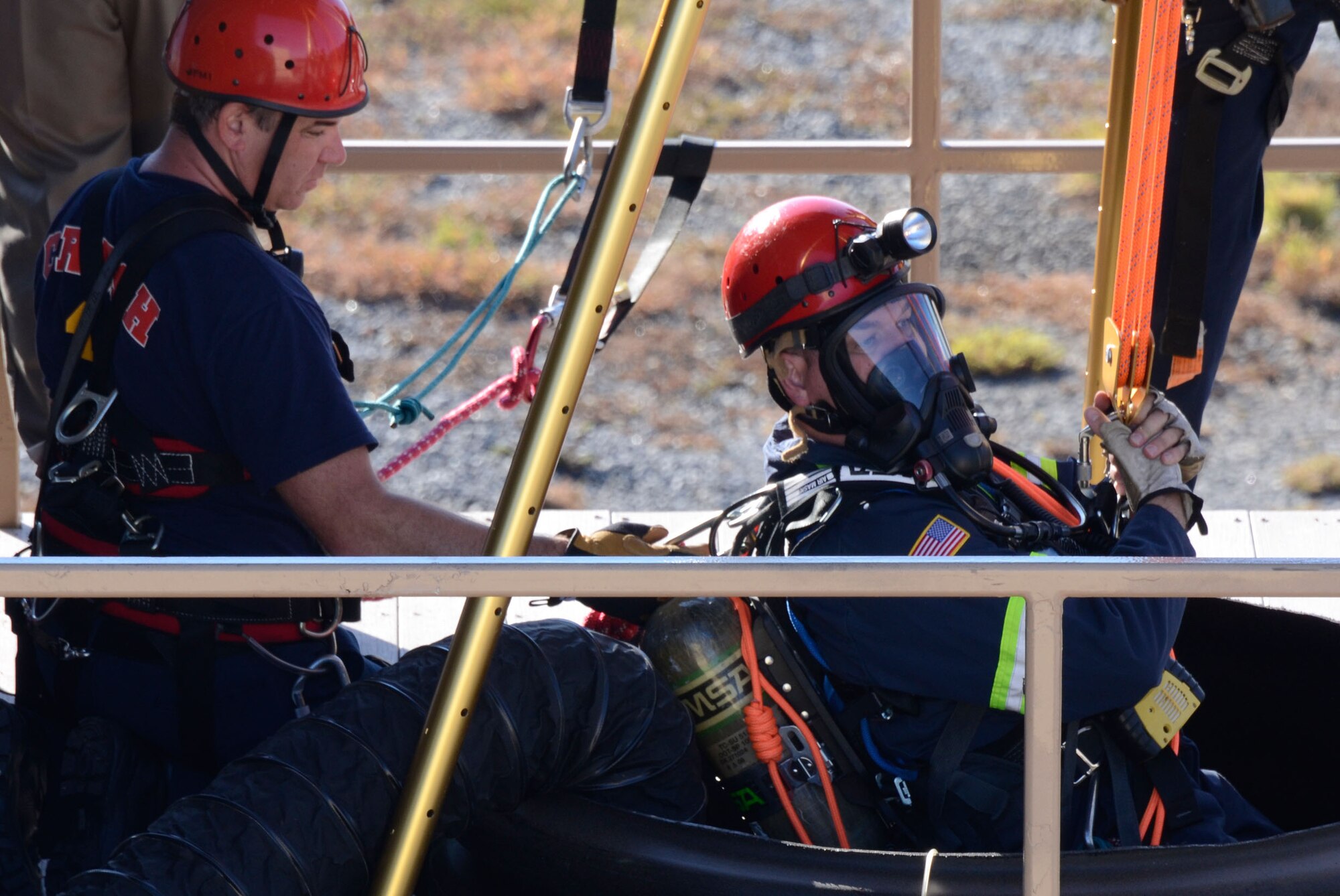 Firefighter Charles Peel is lowered into a 30 foot vertical shaft by fellow fire team member David Gabrielle simulating a rescue of a fallen worker during a confined space exercise here Oct. 17. (U.S. Air Force photo/Don Peek)