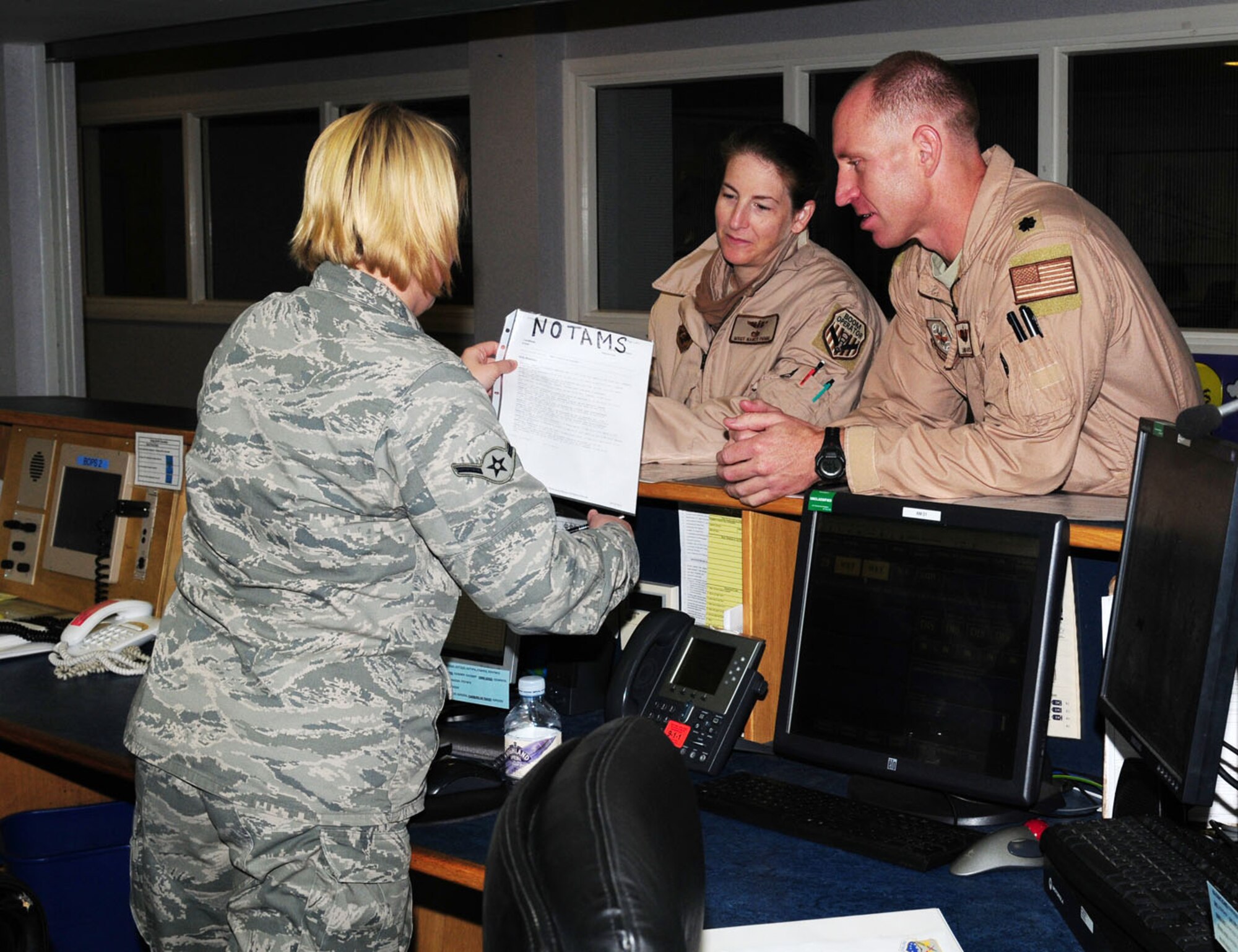 RAF MILDENHALL, England -- Airman Shelby Redmond, 100th Operation Support Squadron Airfield Management flight, talks with transient aircrew, Lt. Col. James Gatch (right), 54th Air Refueling Squadron, Altus Air Force Base, Okla., and Master Sgt. Nancy Primm, 91st Air Refueling Squadron boom operator, from MacDill Air Force Base, Fla., about filing their flight plans, and explains some recent 'Notice to Airmen' information. Airfield management personnel facilitate incoming and outgoing transient aircrew day and night. (U.S. Air Force photo/Karen Abeyasekere)