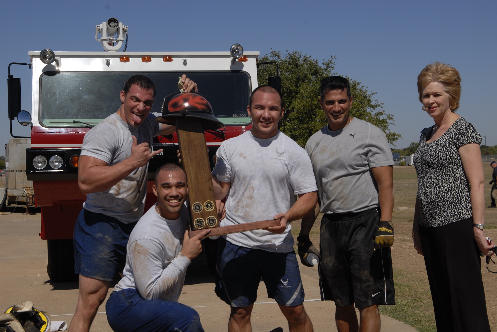 GOODFELLOW AIR FORCE BASE, Texas -- (From left:) Airman 1st Class Duayne Martinez , Senior Airman Jamie Burdette, 2nd Lt. Kirby White and Lt. Col Michael Jones  are recognized for their first place achievement during the firefighter competition muster here Oct. 14. Shelene Black of 1st Community Federal Credit Union awarded the champions with a cash prize for their completion of the challenge in 11 minutes, 21 seconds (U.S. Air Force photo/2nd Lt. Leanne Caballer)