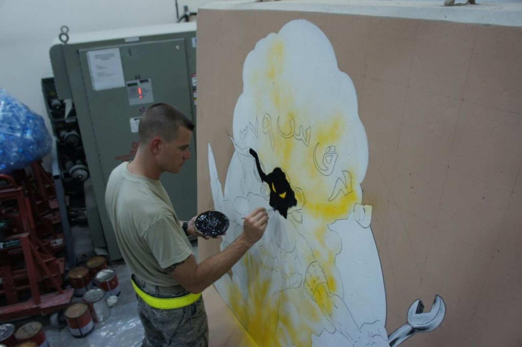 Tech. Sgt. Thomas Young. 379th Expeditionary Maintenance Squadron avionics production supervisor, uses a Q-tip to paint a genie on the 379 EMXS barrier, June 13, 2011, at an undisclosed location in Southwest Asia. Young used various tools available, to include sponges, Sharpies and his fingers to depict the genie with a wrench in one hand and a munition in the other. Young, a native of Orange, Calif., is deployed from Aviano Air Base, Italy. (Courtesy photo)