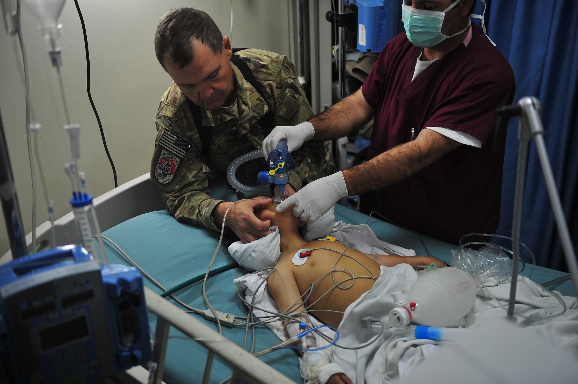 Maj. Marion Foreman aids an Afghan doctor in helping Roquia, an Afghan child breathe, Oct. 10, 2011. Foreman is a critical care nurse with the Special Operations critical care evacuation team deployed from Hurlburt Field, Fla. He's a native of White Castle, La. (U.S. Air Force Photo/Senior Airman Tyler Placie)