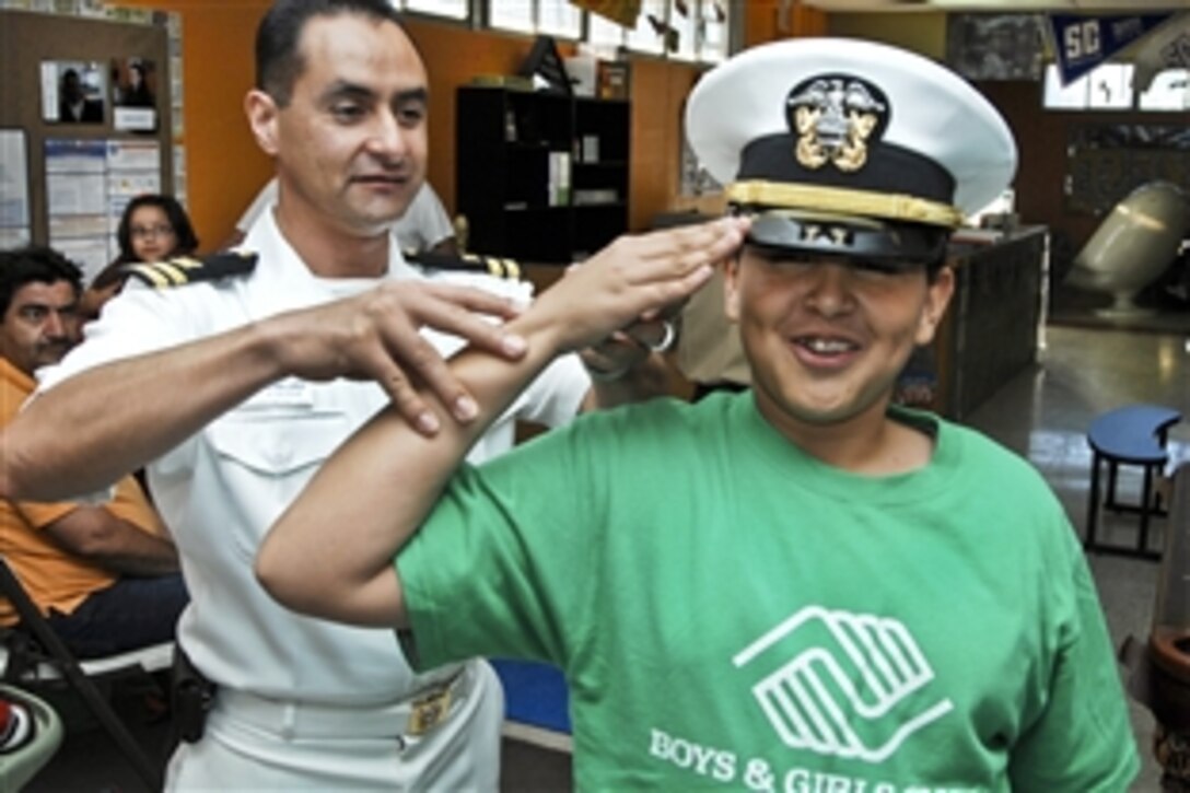 U.S. Navy Lt. Arturo Lopez helps a child salute correctly at Club Delta Boys and Girls Club during El Paso Navy Week 2011 in El Paso, Texas, Oct. 18, 2011. Navy weeks are designed to showcase the investment Americans have made in their Navy and increase awareness in cities that do not have a significant Navy presence. Lopez is assigned to the Navy Operational Support Center El Paso.