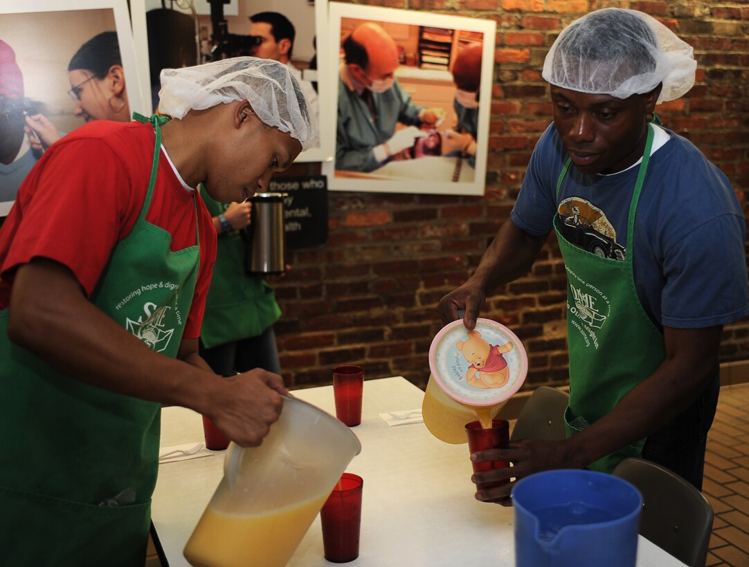Sgt. Simon Medina,left, and Cpl. Judes Grandoit, Marine Barracks Washington motor transportation operators, prepare tables for homeless people by filling cups with orange juice during a So Others Might Eat volunteer event in northwest Washington, D.C., Oct. 20, 2011. Fifteen Barracks Marines volunteered to assist the SOME staff in feeding homeless men and women from the nation's capitol region.