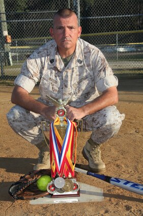 Master Gunnery Sgt. Kevin D. Basso displays a regional trophy and several medals he has won since he started playing softball more than 20 years ago.