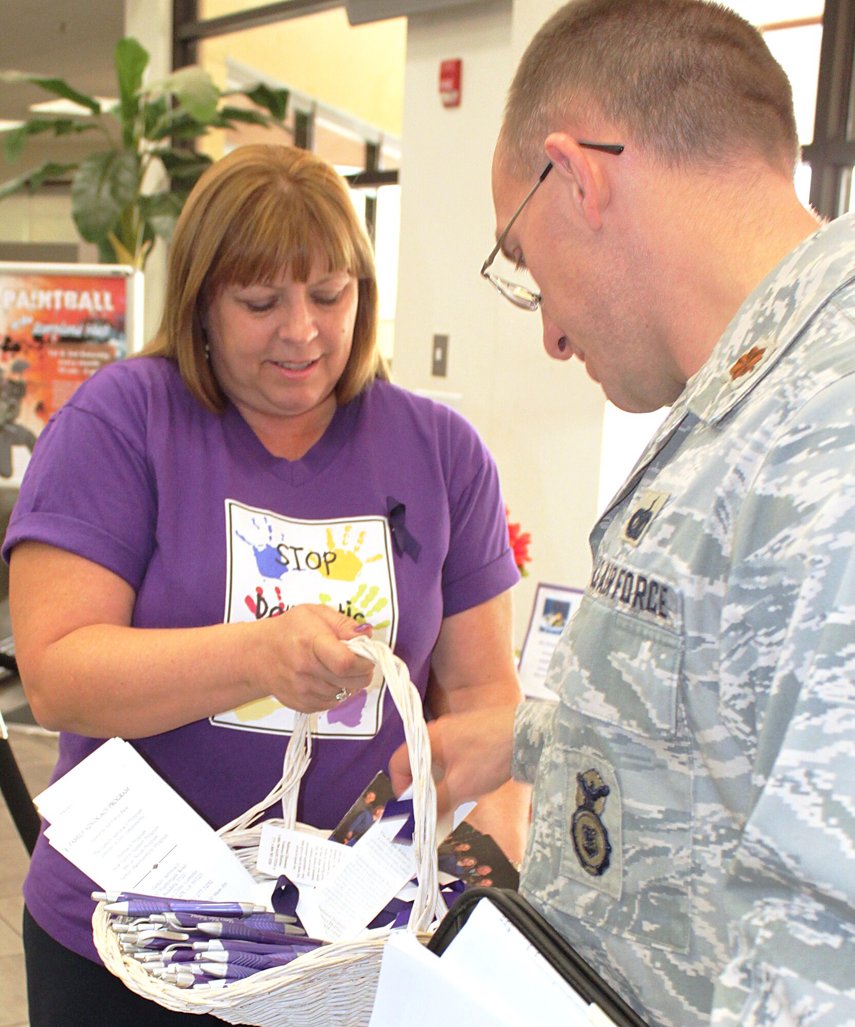 Elaine Estacio, Family Advocacy Outreach Manager, 95th Medical Group provides literature and remniders about Domestic Violence Awareness Month to Maj. Gregory Jarmusz, acting commander, 95th Air Base Wing Security Forces Squadron. (U.S. Air Force phot by Meredith Mingledorff) 