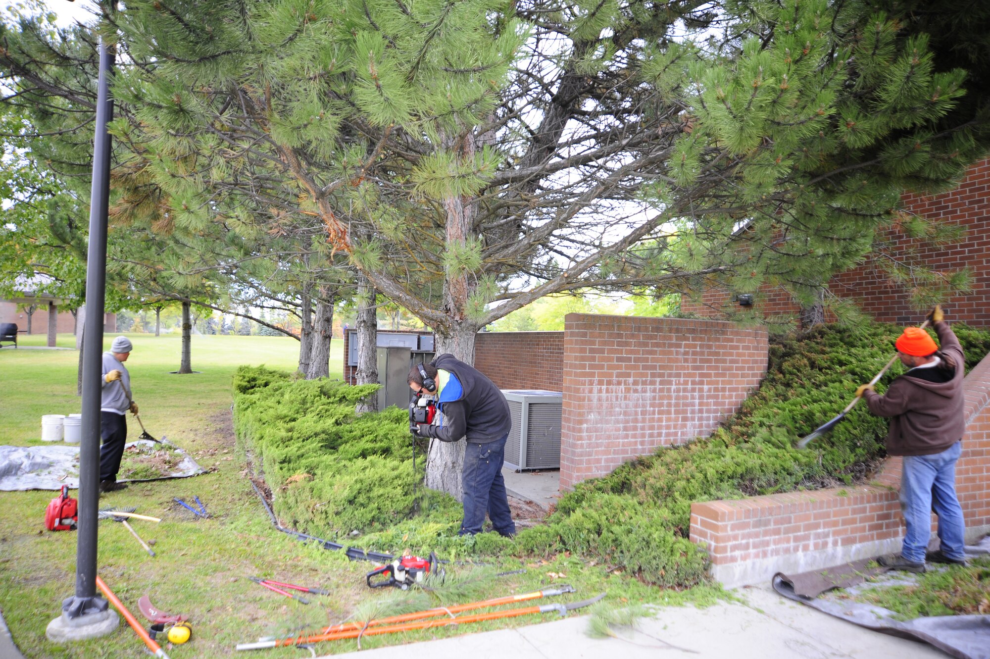 Members from the grounds maintenance section of Skils’kin hedge and rake around a dorm building,  Oct. 13. The grounds section of Skils’kin employs about 60 people The company overall employs more than 160 people. (U.S. Air Force photo/Airman 1st Class Taylor Curry