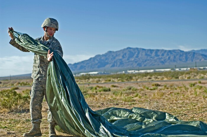 U.S. Air Force Staff Sgt. Jesse Hubbard, 820th RED HORSE airborne power protection craftsman, packs up his parachute during a training mission Oct. 15, 2011, at Nellis Air Force Base, Nev. RED HORSE Airmen perform airdrop missions to stay current on training and certifications, enabling them to perform jump missions and operate their own drop zones. (U.S. Air Force photo by Airman 1st Class Matthew Lancaster/Released)