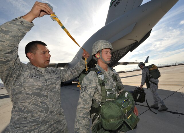 From left, U.S. Air Force Tech. Sgt. Francisco Corona, 6th Combat Training Squadron joint terminal attack controller instructor, performs a (JMPI) Jumpmaster Personnel Inspection on Staff Sgt. Jesse Hubbard, 820th RED HORSE airborne flight airborne power production journeyman, prior to a jump mission Oct. 15, 2011, at Nellis Air Force Base, Nev.  RED HORSE and 6 CTS Airmen perform airdrop missions to stay current on training and certifications, enabling them to perform jump missions and operate their own drop zones.(U.S. Air Force photo by Senior Master Sgt.  Kevin Gruenwald/Released)