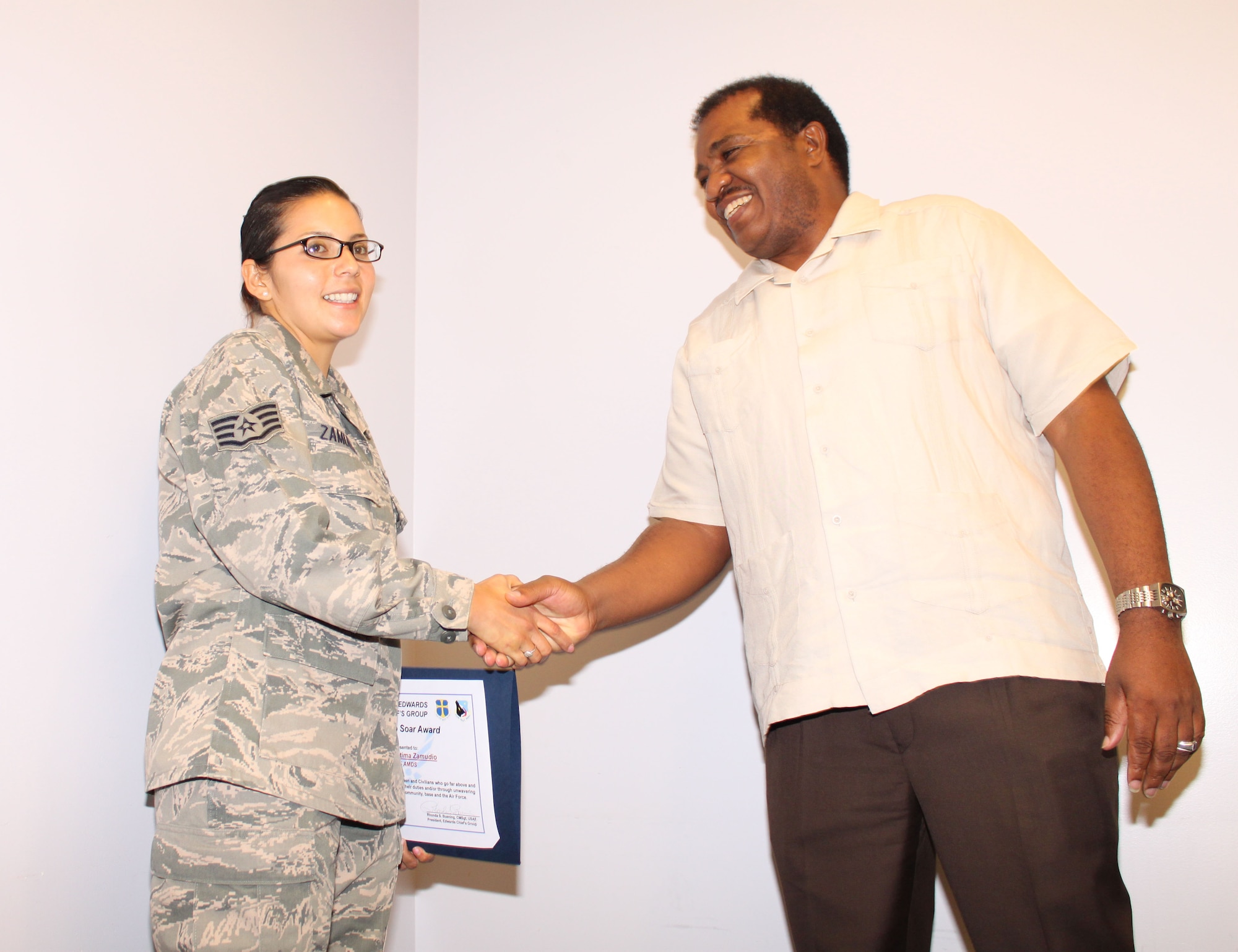 Surprised by the Edwards Chiefs Group, Staff Sgt. Fatima Zamudio, public health technician, 95th Aerospace Medicine Squadron, is presented the Dare to Soar Award by retired Chief Master Sgt. Nathan M. Dixon Jr. , chief, Maintenance Training Division, 412th Maintenance Group. (U.S. Air Force Photo by Meredith Mingledorff) 
