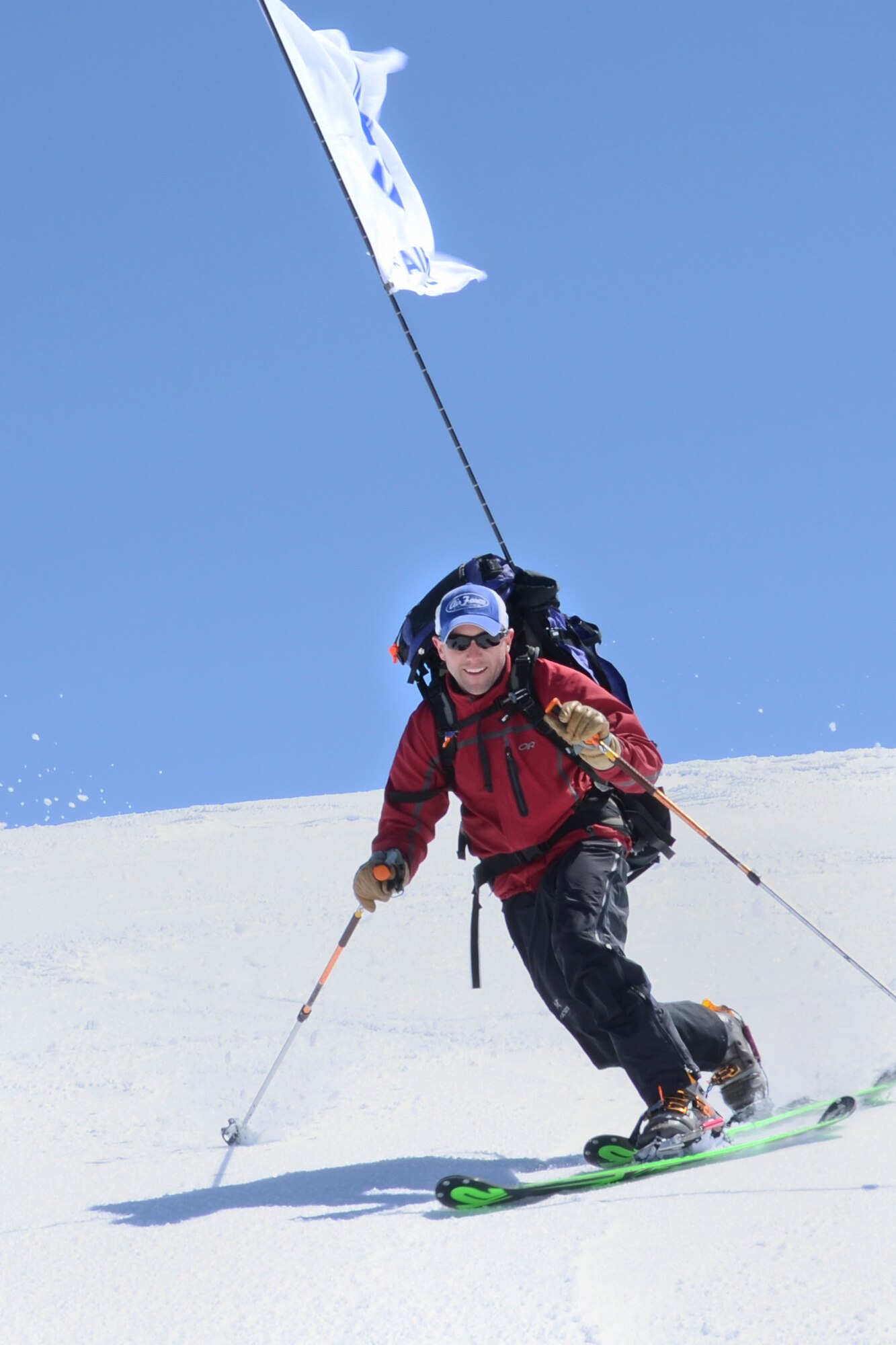 Maj. Rob Marshall, CV-22 Osprey functional test pilot in Alamogordo, N.M., skis down the summit of Australia?s highest mountain, Mount Kosciuszko, with the US Air Force flag flying above, Oct. 3, 2011. This was part of the U.S. Air Force 7 Summits Challenge, where a group of Airmen have made the goal of climbing to the top of each continent?s highest mountain.  (Courtesy photograph)