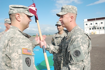 Capt. Mike Crivello, C Company commander of the 1st Battalion 228th Regiment, receives the company's guidon from Lt. Col. Michael Breslin, commander of the 1st Battalion, 228th Aviation Regiment during a change of command ceremony Oct. 21, 2011 at Soto Cano Air Base, Honduras. Maj. Seth Swartz, outgoing C Company commander, takes part in the ceremony. (U.S. Air Force photo/Capt. Candice Allen)