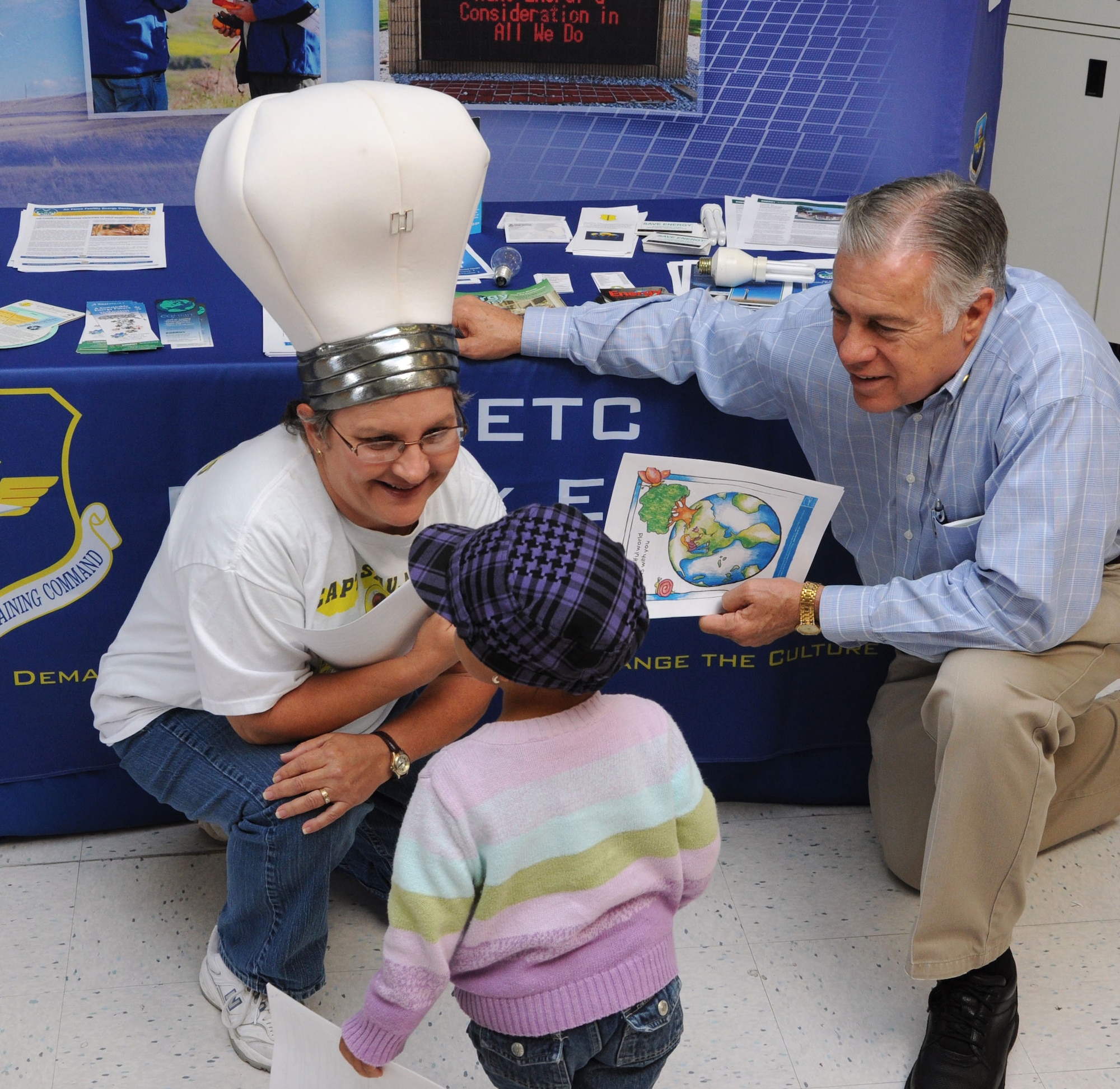 GOODFELLOW AIR FORCE BASE, Texas—Mary Lumsdon, base energy manager, and Randy Wood, recourse efficiency manager, talk to  Joelle Griffis, 3, about energy conservation at the Base Exchange Oct. 20.  October is Energy Awareness Month. (U.S. Air Force photo/Airman 1st Class Jessica Keith)