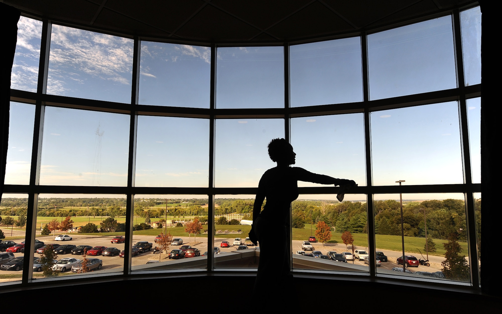 U.S. Air Force Airman Corey Moodey, 55th Force Support Squadron, cleans windows overlooking the Kenney Gate as part of the wing dormitory clean-up at Offutt Air Force Base, Neb., Sept. 24.  The massive window is the architectural focal point of Tuskegee Hall, Offutt?s newest dorm.  (U.S. Air Force photo by Josh Plueger/Released)
