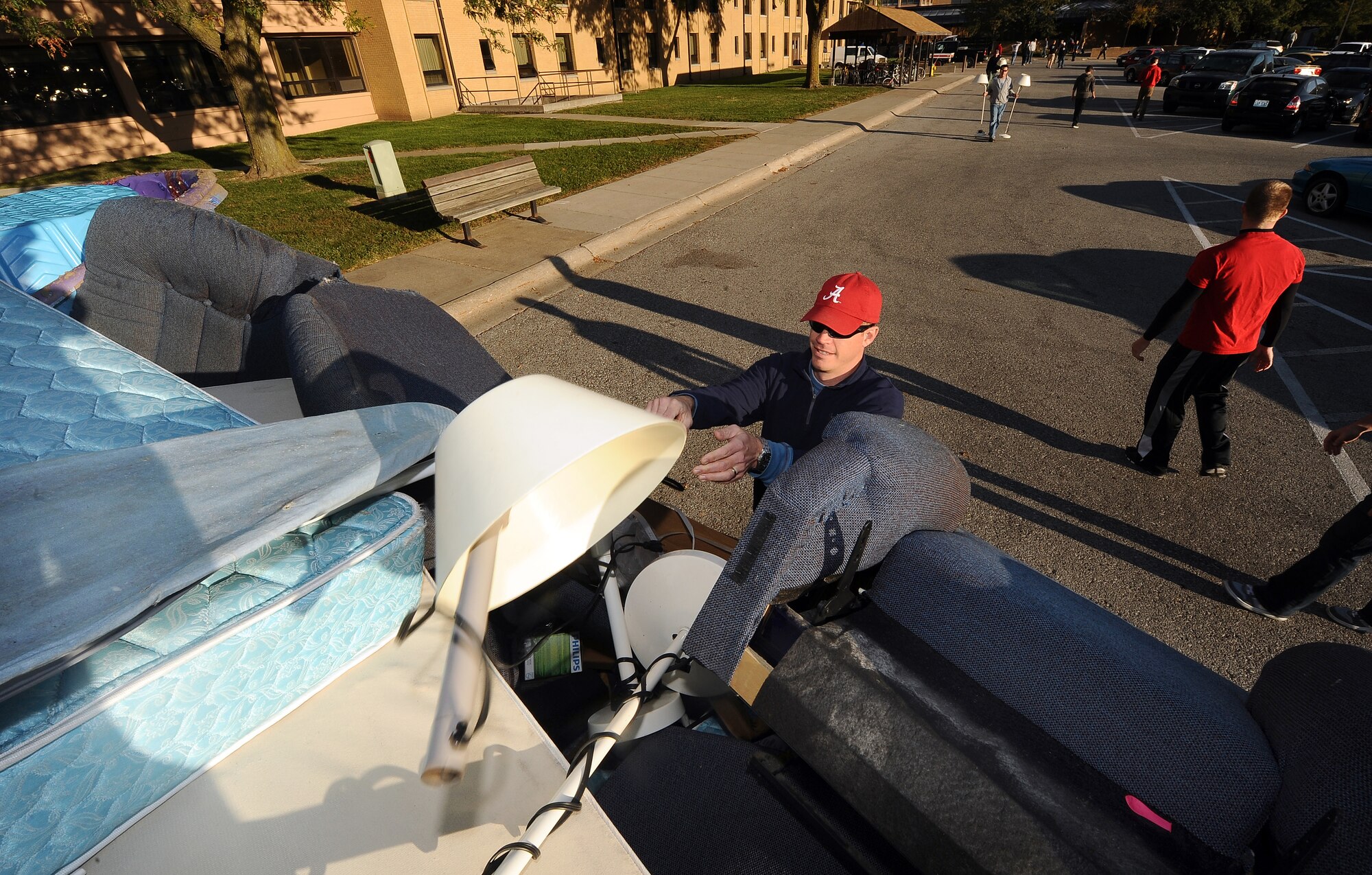 U.S. Air Force Lt. Col. Jeff Ford, 97th Intelligence Squadron commander, tosses a broken lamp into a dumpster located in front of Whiteman Hall dormitories while helping with the dorm clean-up at Offutt Air Force Base, Neb., Sept. 24.  Team Offutt members donated their time on a Saturday morning to clean up the four dorms on base. (U.S. Air Force photo by Josh Plueger/Released)