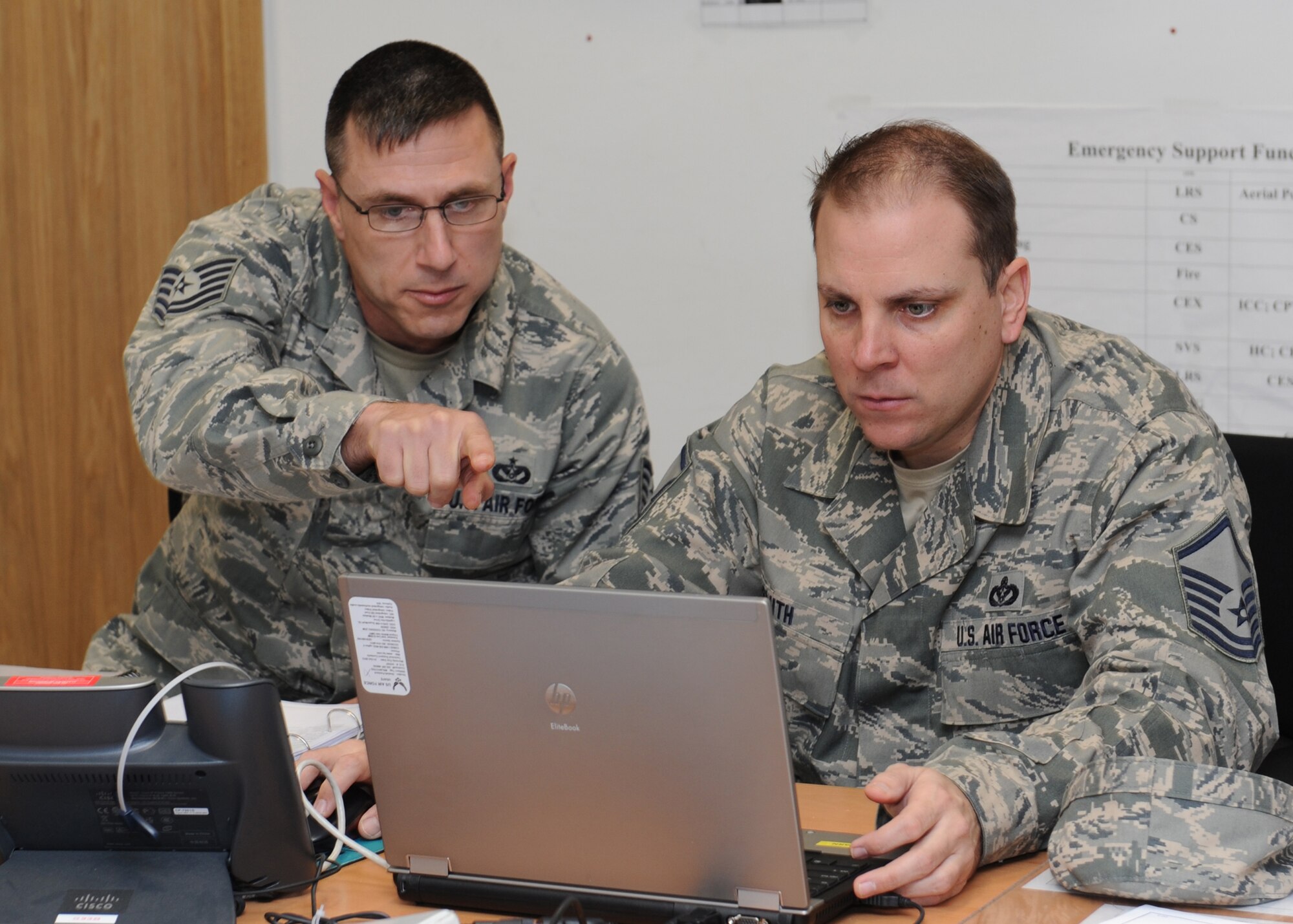 RAF MILDENHALL, ENGLAND -- Tech. Sgt. Chris Mahafey and Master Sgt. Thomas Smith, both of the 100th Civil Engineering Squadron, review data Oct. 20, 2011, during an Environmental Safety Occupational Health Compliance Assessment and Management Program assessment. The ESOHCAMP assessment, designed to help commanders assess the status of their environmental, safety and occupational health programs, ran from Oct. 17 to 21 at the base. (U.S. Air Force photo by Tech. Sgt. Neal Joiner)