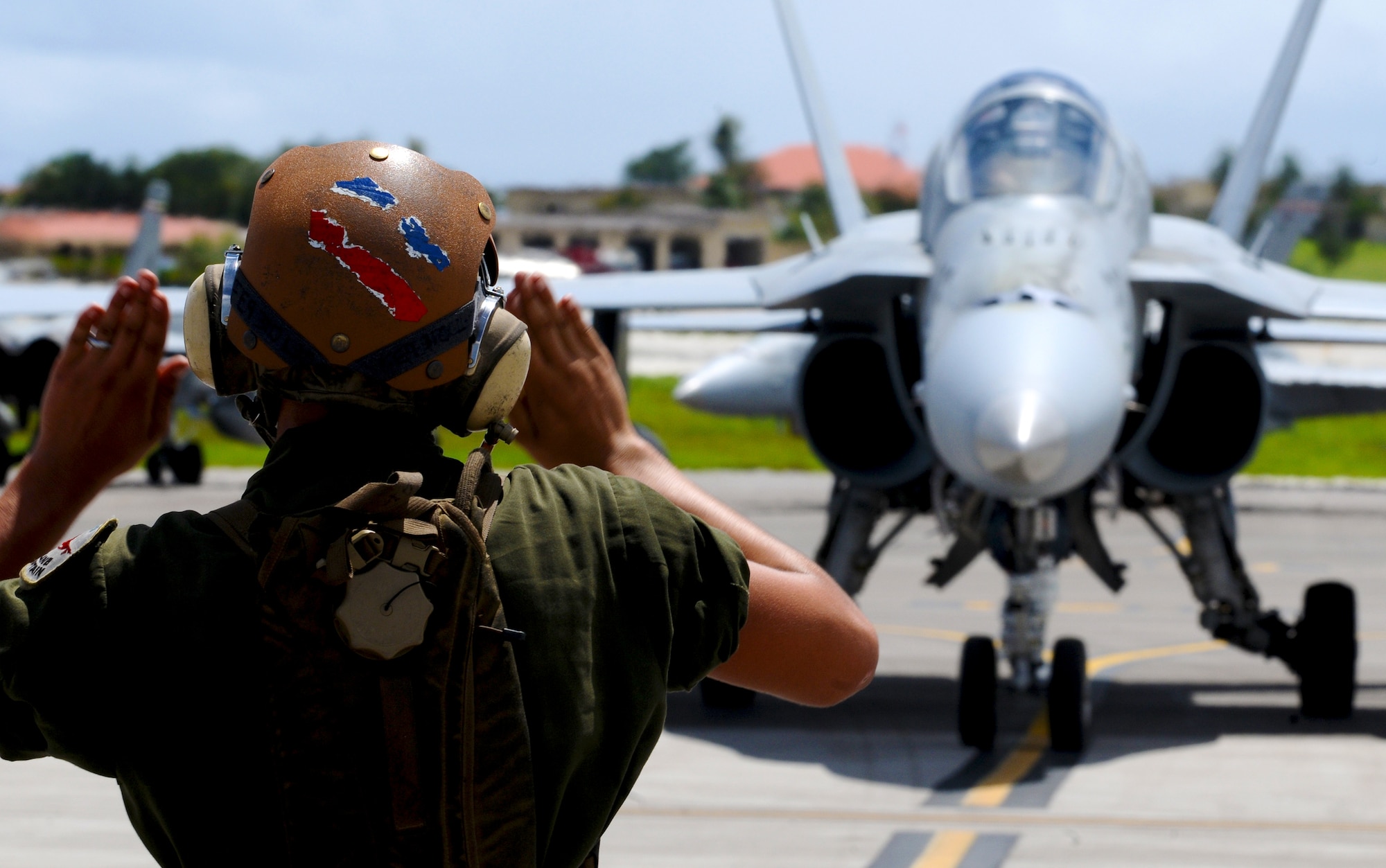 ANDERSEN AIR FORCE BASE, Guam—A U.S. Marine Corps crew chief guides an F/A-18 Hornet fighter jet into its parking space here, Oct. 20. Several units from Marine Corps Air station Iwakuni, Japan, came to conduct aerial and ground training at Andersen. (U.S. Air Force photo by Senior Airman Benjamin Wiseman/Released)