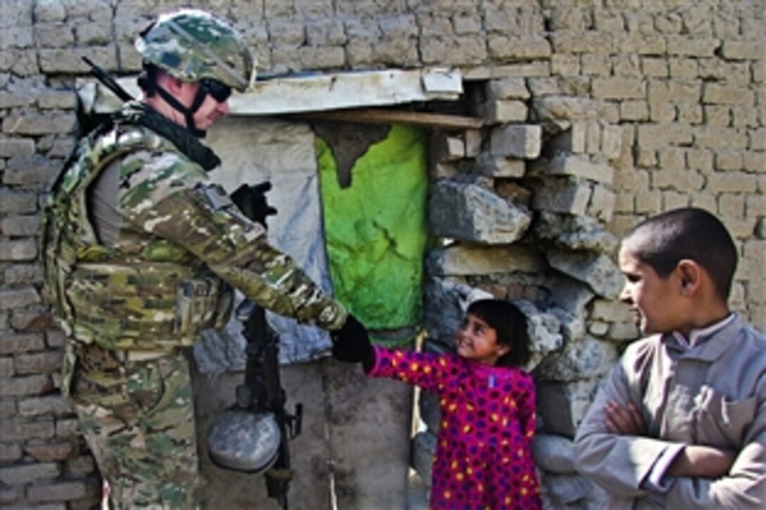 Staff Sgt. Joe Tate shakes an orphan's hand at an Operation Outreach visit to a local refugee camp in Kabul, Afghanistan, Oct. 20, 2011. Operation Outreach is a volunteer organization in Kabul, Afghanistan made up of U.S. military, International Security Assistance Force troops and civilians that help give impoverished children and families a better quality of life.