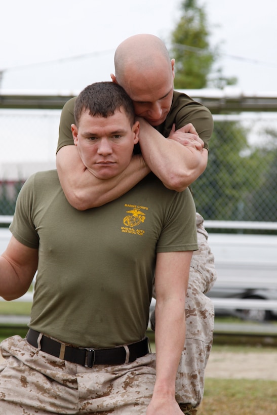 Sgt. Roger Kerstetter, Marine Corps Martial Arts instructor, performs a blood choke on Sgt. Jon Barge, MCMAP instructor, as a demonstration during Jane Wayne Day here Oct. 21. Three MCMAP instructors taught spouses a variety of MCMAP moves during the event.