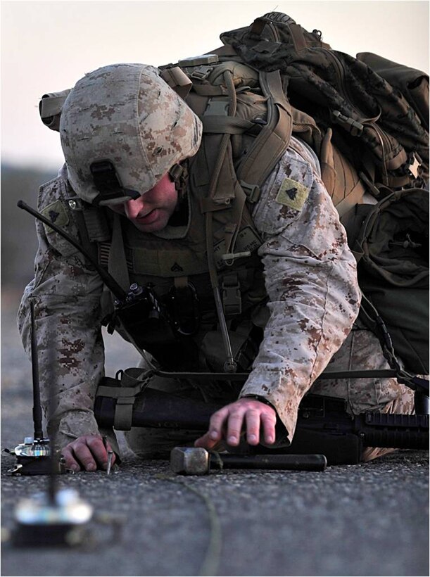 U.S. Marine Corporal Bryan Reilly, Marine Air Traffic Control Mobile Team air traffic controller, 22nd Marine Expeditionary Unit, reaches for a hammer while setting up an austere landing zone at Chabelley Airfield, Djibouti, October 21. Reilly is originally from Middlesex, New Jersey. He is part of a six-man team tasked with setting up landing zones for aircraft in austere environments.