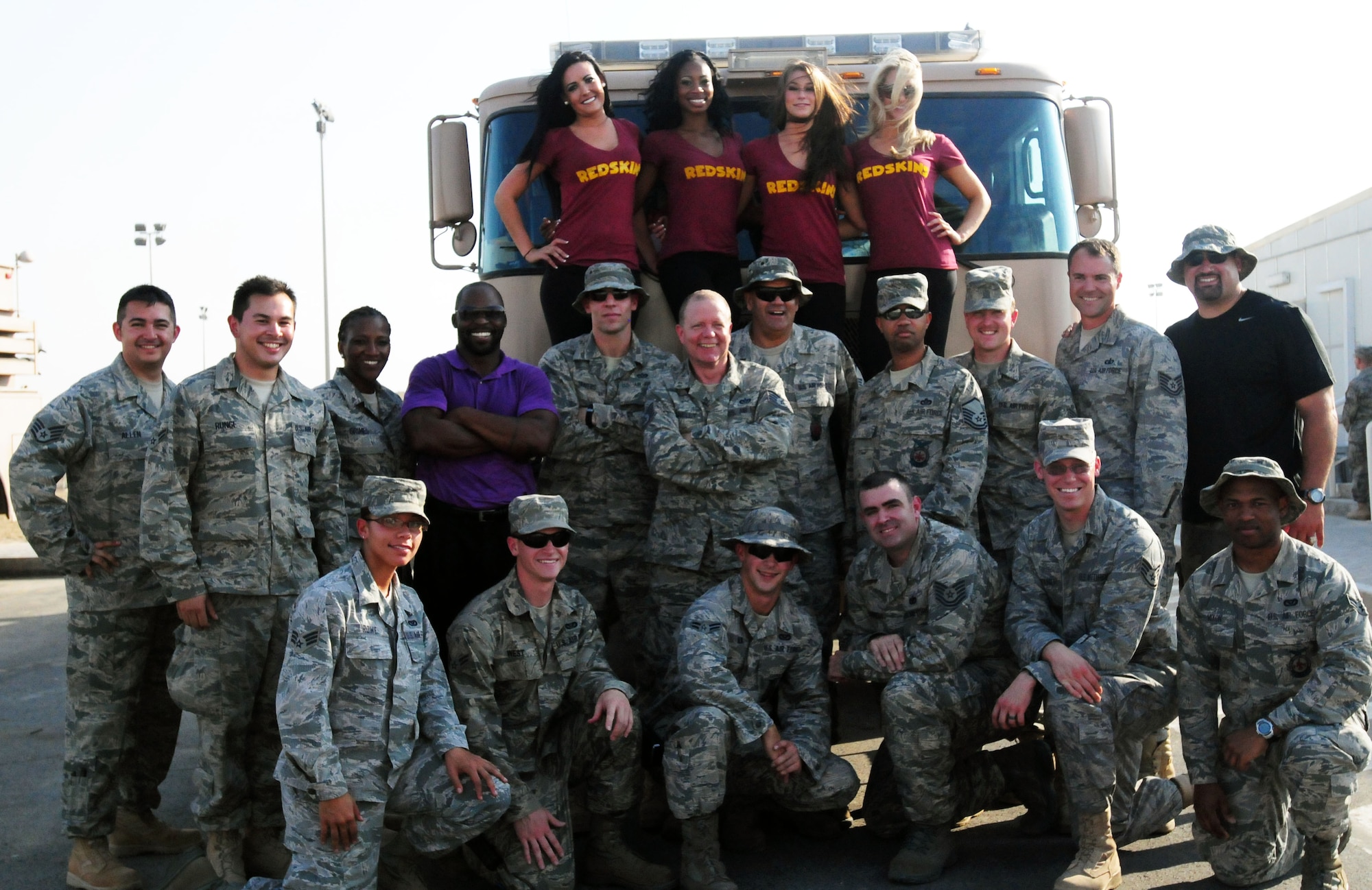 NFL players Marco Rivera and R.W. McQuarters, four members of the Washington Redskins Cheerleaders and Top Cover, the U.S. Air Forces Central Command band, pose with firefighters at the 380th Air Expeditionary Wing Oct. 20, 2011. The football players and cheerleaders visited the base as part of an Armed Forces Entertainment tour for deployed service members. Top Cover visited the base during their tour to bases in the area of responsibility. (U.S. Air Force photo/Capt. Gina Vaccaro McKeen)