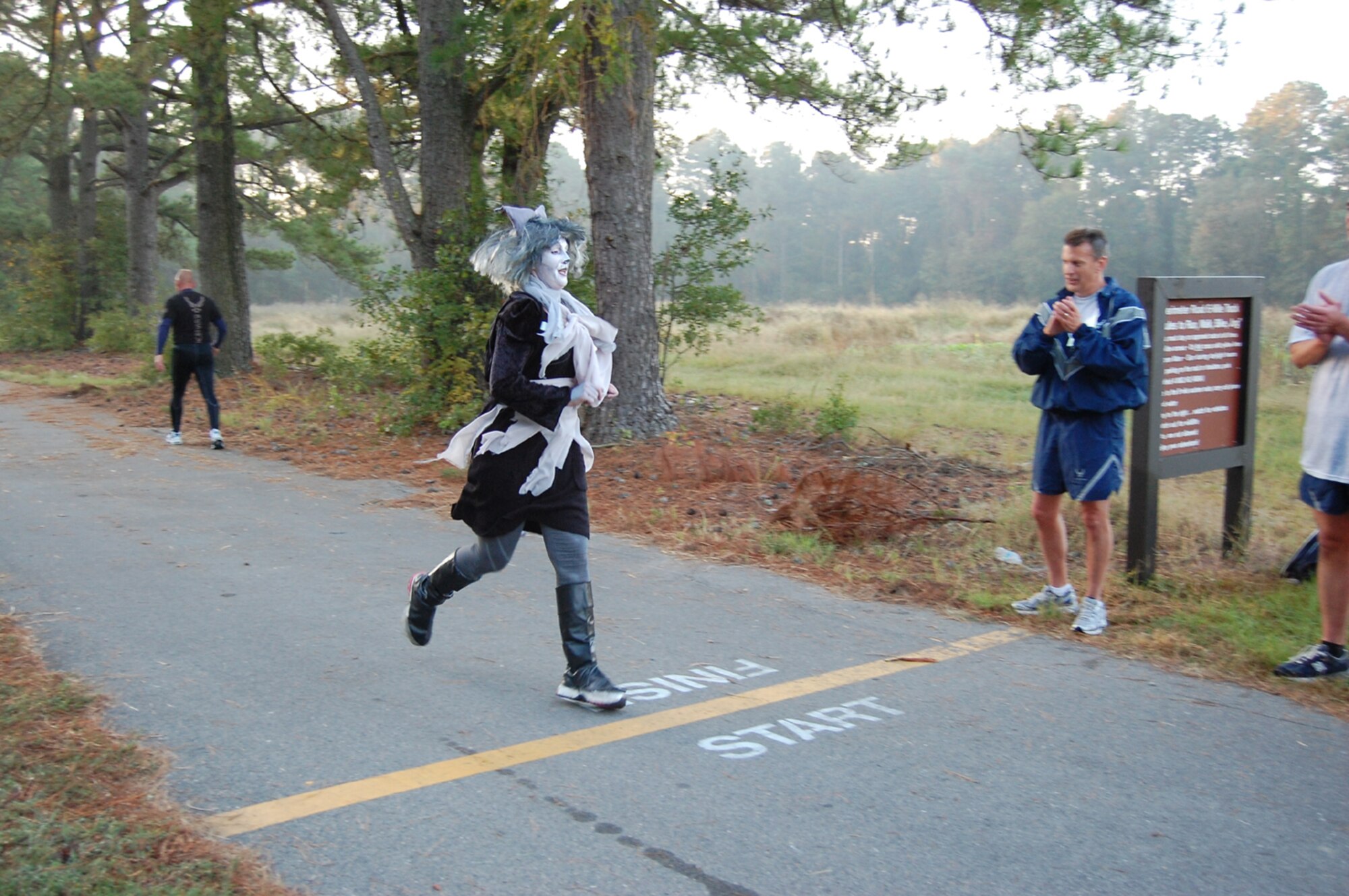 Lt. Col. Cherie Roff crosses the finish line as Grizabella the Glamour Cat during the wing's semi-annual Warrior Run on Oct. 23, 2011. Roff won the third place trophy for her creative costume. (USAF photo by SSgt. Mark Thompson, 916ARW/PA)