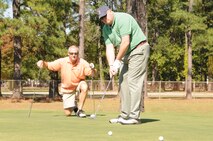 Lt. Col. Brian Davis gets a close look as Master Sgt. Kevin Hughes lines up his putt during the wing's golf tournament to celebrate 25 years of re-activation. (USAF photo by SSgt. Mark, Thompson, 916ARW/PA)