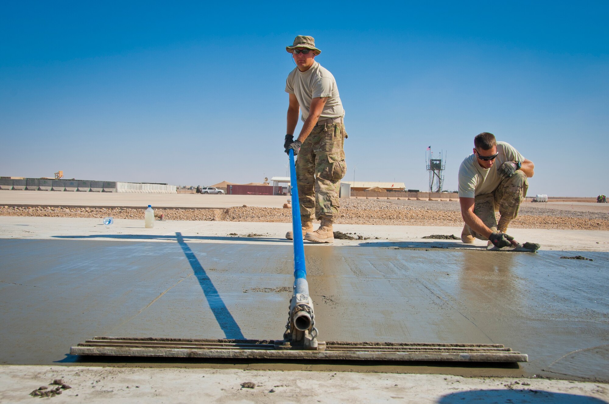 CAMP DWYER, Afghanistan -- Airman 1st Class Adam Lorenz (center) and Senior Airman Paul Loughery (right), 809th Expeditionary RED HORSE Squadron Det. 1, smoothen out the freshly set concrete at a new construction site at Camp Dwyer, Afghanistan, Oct. 18. Lorenz and his fellow heavy equipment operators set the concrete foundations of two future buildings that will be used to host an Army helicopter medevac unit at Camp Dwyer. (U.S. Air Force photo by Senior Airman David Carbajal)