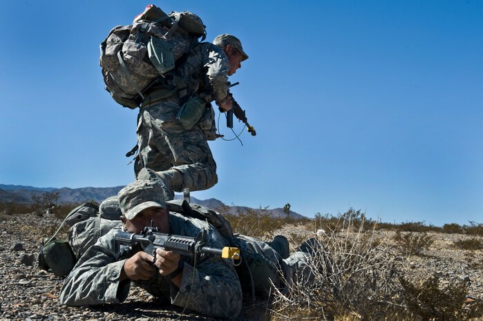 From left, U.S. Air Force Tech. Sgt. Richard Holder, 820th Combat Operations Squadron security forces craftsman from Moody Air Force Base, Ga., shoots while Staff Sgt. Giovanii Pacheco, 96th Ground Combat Training Squadron security forces craftsman from Eglin Air Force Base, Fla., runs from enemy fire in a rehearsal training mission during the Ranger Assessment and Selection Course Oct. 21, 2011, at the Nevada Test and Training Range. Airmen must attend the RAS course before going to the U.S. Army Ranger School, which is designed to train armed forces personnel to conduct combat operations within enemy lines. (U.S. Air Force photo by Airman 1st Class Daniel Hughes/Released)