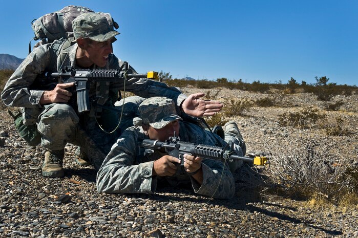 From left, U.S. Air Force Tech. Sgt. Richard Holder, 820th Combat Operations Squadron security forces craftsman from Moody Air Force Base, Ga., points toward enemy activity as Staff Sgt. Giovanii Pacheco, 96th Ground Combat Training Squadron security forces craftsman from Eglin Air Force Base, Fla., aims down range during a training mission at the Ranger Assessment and Selection Course Oct. 21, 2011, at the Nevada Test and Training Range. Airmen must attend the RAS Course before going to the U.S. Army Ranger School, which is designed to train armed forces personnel to conduct combat operations within enemy lines. (U.S. Air Force photo by Airman 1st Class Daniel Hughes/Released)