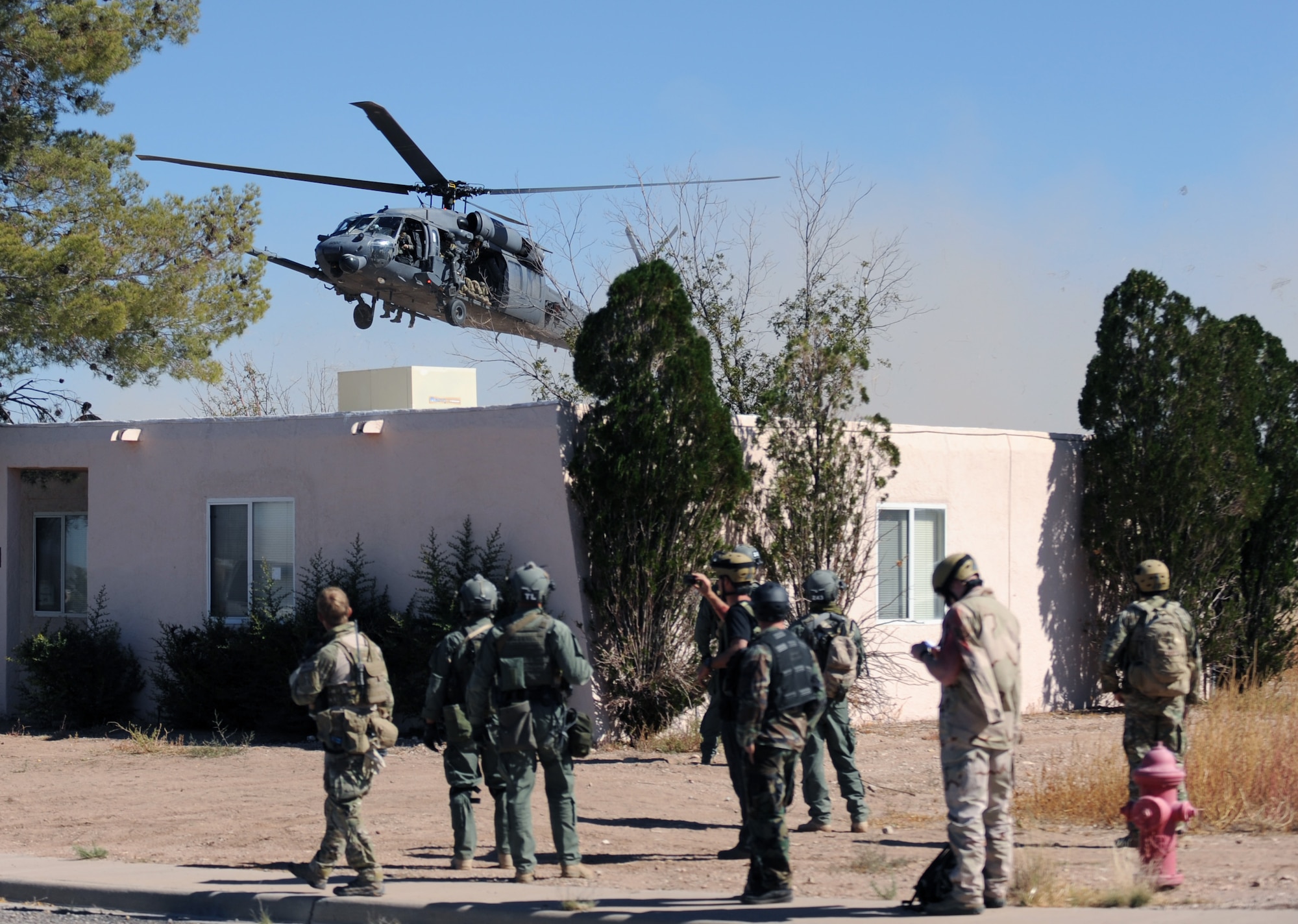PLAYAS, N.M. – Border Patrol’s tactical unit and pararescuemen wait for a helicopter to land so they can transport two hostages after successfully rescuing them from captivity during a hostage rescue scenario at Playas Training and Research Facility in New Mexico Oct. 20. Playas is a training facility that military branches and government agencies use to practice real world scenarios without the worry of injury. (U.S. Air Force photo/Airman 1st Class Michael Washburn)