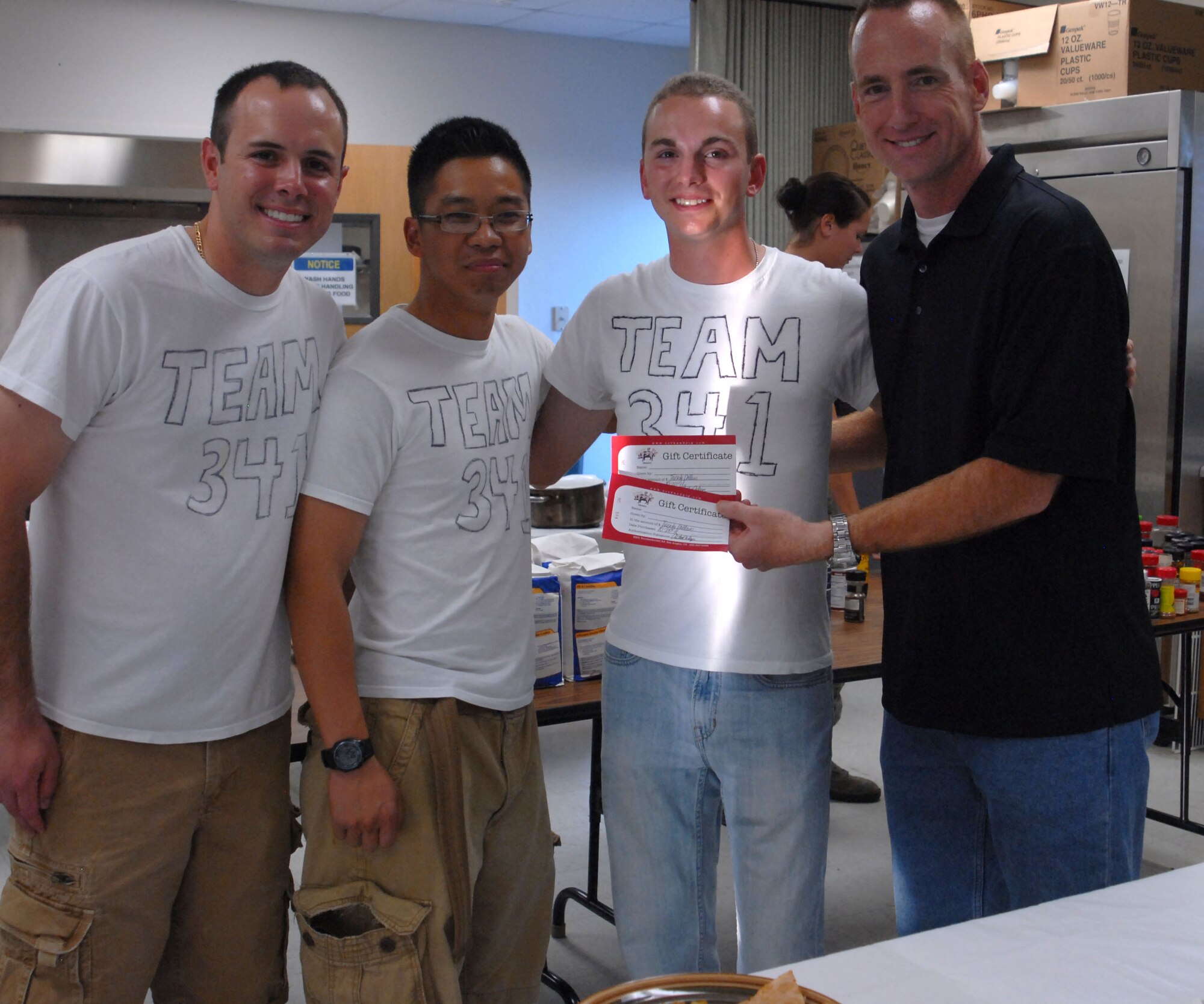 GOODFELLOW AIR FORCE BASE, Texas-- Chaplain (Capt.) Joel Kornegay, presents Team 341, Airman 1st Class Michael Leon, Airman 1st Class Daniel Hoang and Airman 1st Class Kyle Baldwin, with certificates to a local restaurant in recognition of their victory during Goodfellow’s version of the Iron Chef competition at Crossroads here Oct. 22. The two teams, both comprised of 315th Training Squadron students had one hour to create three dishes spotlighting the secret ingredient: plantains. (U.S. Air Force photo/Airman 1st Class Jessica Keith)
