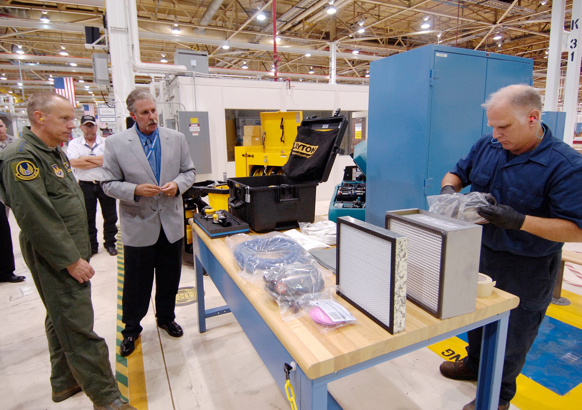 Gen. Donald Hoffman, commander of Air Force Materiel Command, and Tinker’s Jim Crofoot watch sheet metal mechanic Danny Humpula don protective gear in the 551st Commodities Maintenance Group’s B1 Stabilizer Shop, Bldg. 9001. During his two-day visit Oct. 13 and 14, the commander saw new sanding equipment that contains 98-99 percent of contaminants and is part of Tinker’s benchmark safety program. (Air Force photo by Margo Wright)