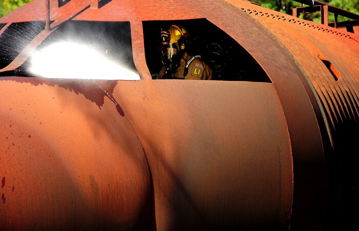 Jeffrey Guthrie responds to a simulated interior fire during a training exercise at Joint Base Charleston - Air Base. The interior burn inside the static training aircraft allows Team  Charleston fire fighters the ability to practice  their fire-response abilities in case of an actual emergency. Guthrie is a fire fighter with the 628th Civil Engineer Squadron. (U.S. Air Force Photo/ Staff Sgt. Clay Lancaster )