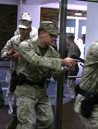 Lance Cpl, Michael J. Dandrea, a station Provost Marshal’s Office military policeman helps to breach a main entrance to a building during a training exercise at a midrise here Tuesday. Military policemen breached the building and played out their scenarios in groups of four. They learned to work together and as a single unit to help maintain speed and accuracy while performing close quarter techniques and putting knowledge of combat to the test.