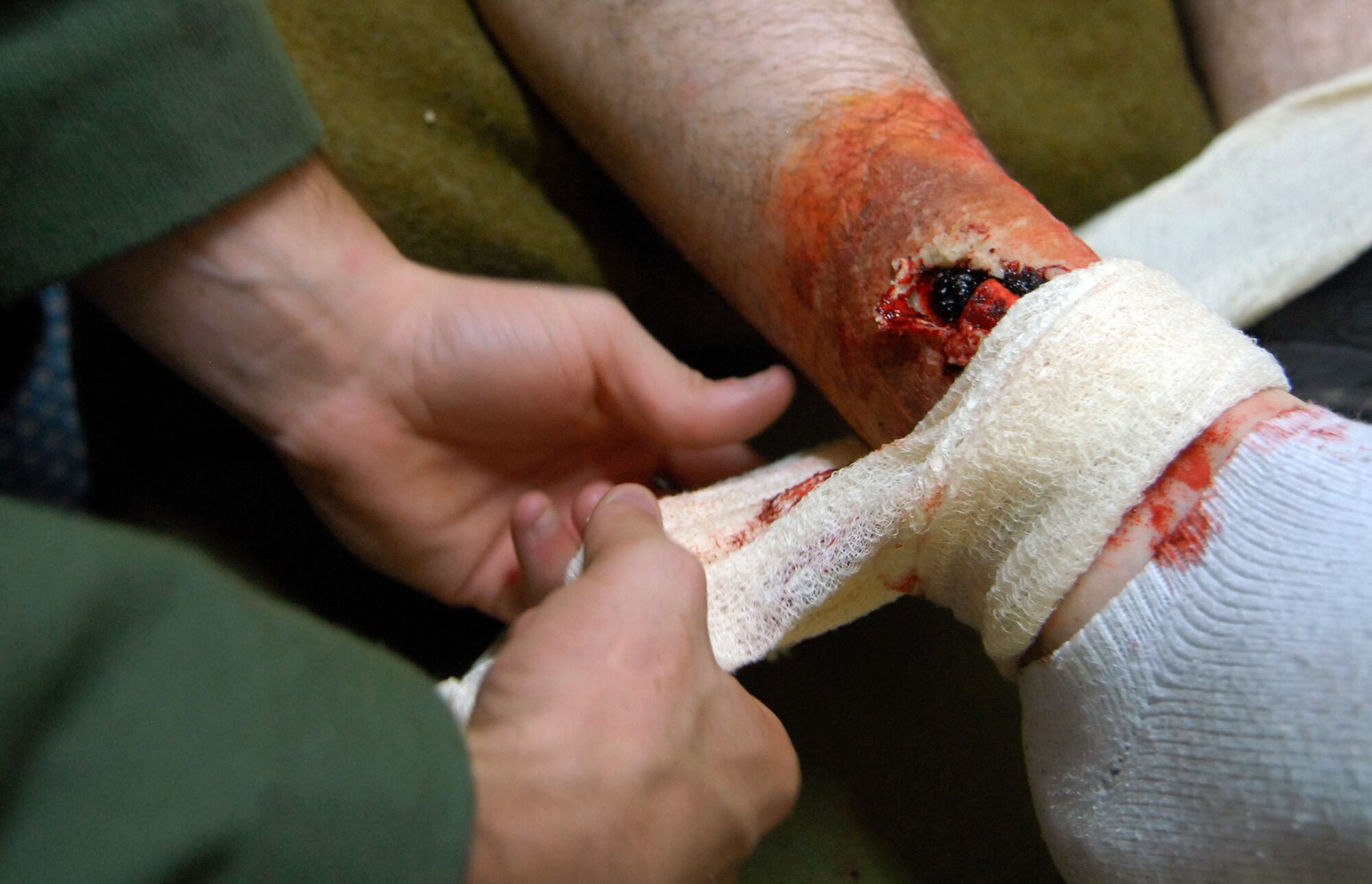 An Airman from the 961st Airborne Air Control Squadron wraps a mock wound after an exercise inject during local operational readiness exercise at Kadena Air Base, Japan, Oct. 25. Airmen from the 961st AACS performed self aid and buddy care on the mock victim to help prepare them for real world contingencies if need be. Different scenarios such as mock bomb victims are presented to Airmen to help them perform under pressure and train together as teams. (US Air Force photo/Senior Airman Sara Csurilla)