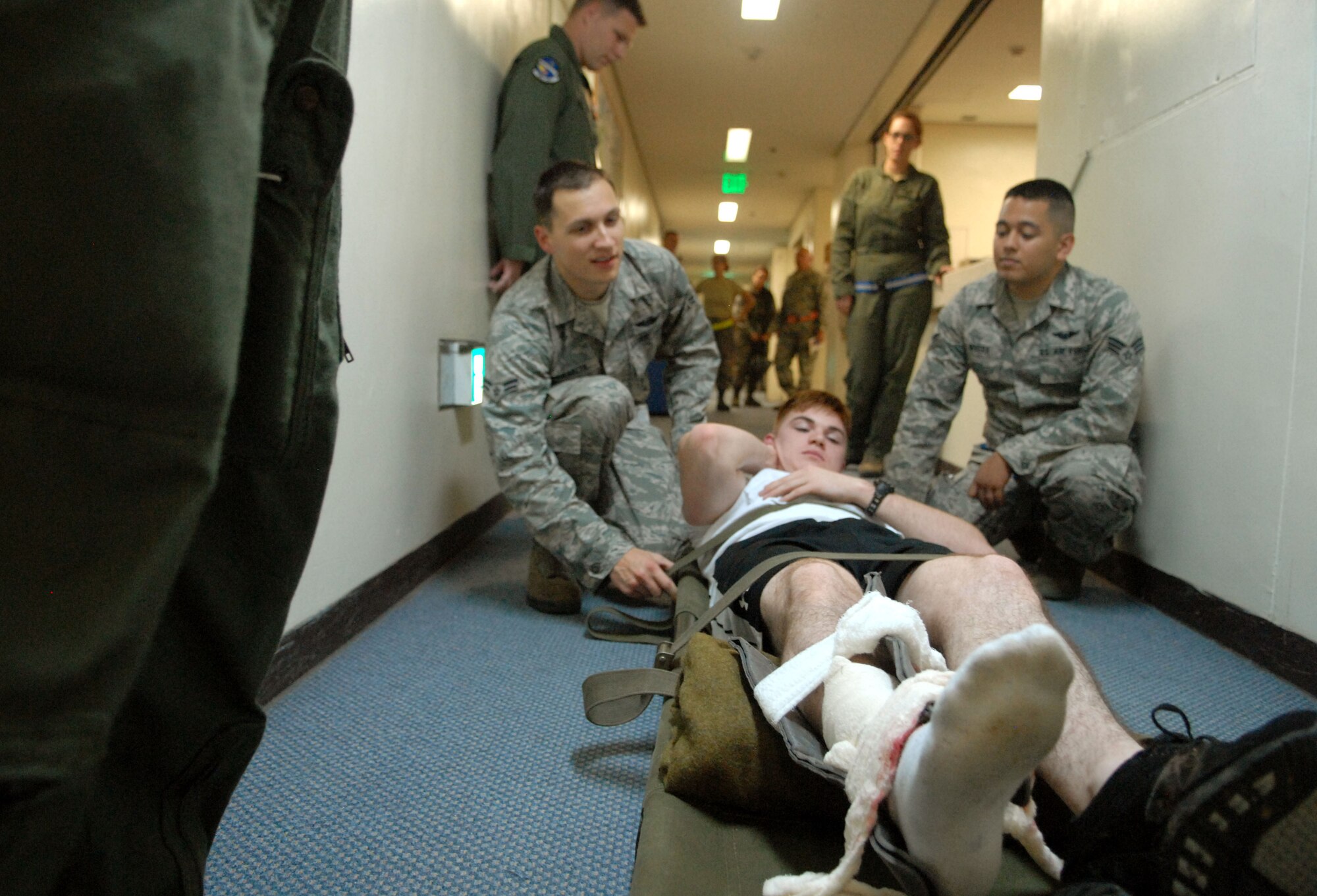U.S. Air Force Airman 1st Class James Makaryk and Senior Airman Josh Rivera, both from the 961st Airborne Air Control Squadron, set Airman 1st Class Jonathan Royal, 18th communications Squadron and mock victim, down on a stretcher after performing self aid buddy care on him during Beverly High 12-1, a local operational readiness exercise at Kadena Air Base, Japan, Oct. 25. The LORE is an exercise Team Kadena Airmen participate in to be prepared for real world contingencies if need be. Different scenarios such as mock bomb victims are presented to Airmen to help them perform under pressure and train together as teams. (US Air Force photo/Senior Airman Sara Csurilla)
