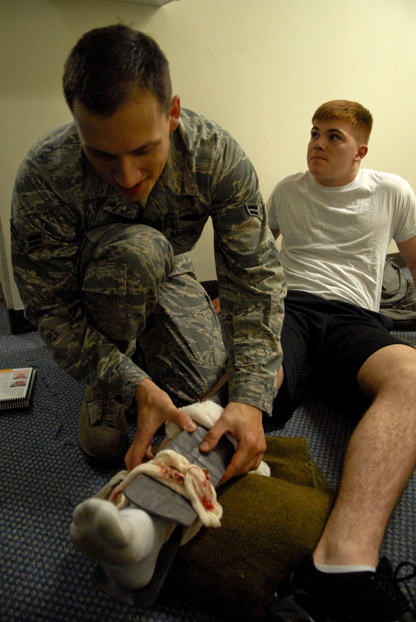 U.S. Air Force Airman 1st Class James Makaryk, 961st Airborne Air Control Squadron, performs self aid buddy care on Airman 1st Class Jonathan Royal, 18th communications Squadron and mock victim, during Beverly High 12-1, a local operational readiness exercise at Kadena Air Base, Japan, Oct. 25. The LORE is an exercise Team Kadena Airmen participate in to be prepared for real world contingencies if need be. Different scenarios such as mock bomb victims are presented to Airmen to help them perform under pressure and train together as teams. (US Air Force photo/Senior Airman Sara Csurilla)