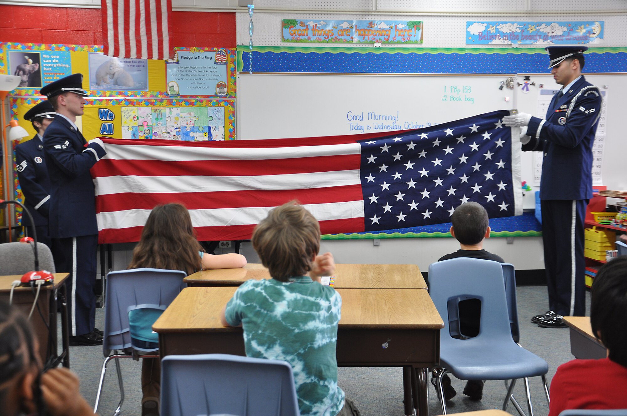 ANCHORAGE, Alaska -- Airman 1st Class Timothy Washington, left, and Airman 1st Class Jose Mejia, perform the two-man fold of the US flag for a third grade class Oct. 19. Joint Base Elmendorf-RIchardson honor guard members visited Abbott Loop Elementary school to demonstrate proper flag folding procedures as well as other military movements to students. (U.S. Air Force photo/Senior Airman Cynthia Spalding) 