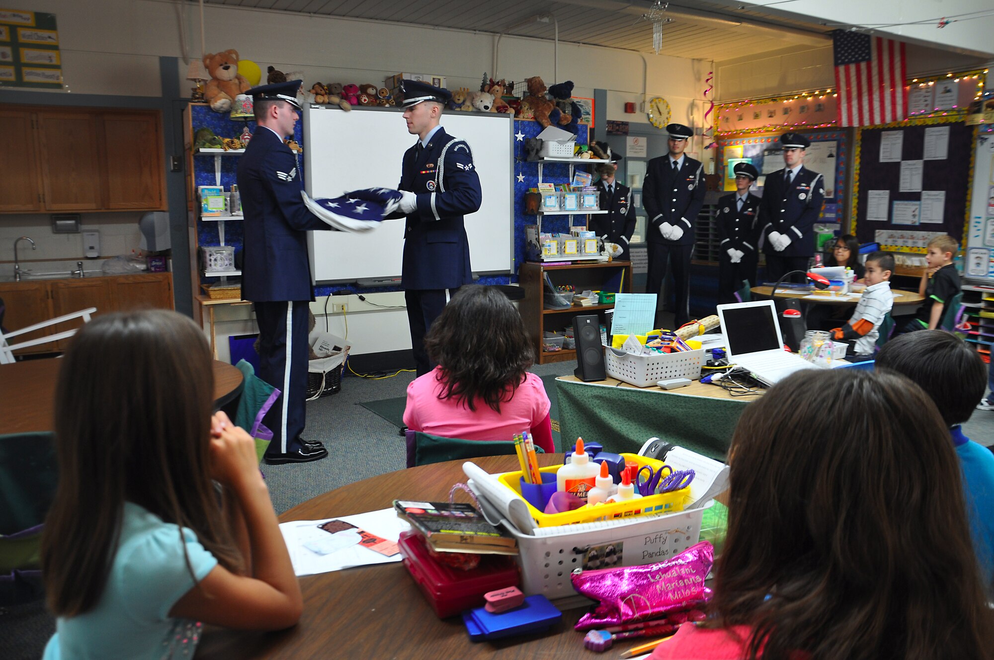 ANCHORAGE, Alaska -- Senior Airman Larry Markwell, left, and Airman 1st Class Josh Lemke perform the two-man fold of the US flag for a class of third graders at Abbott Loop Elmentary Oct. 19. Joint Base Elmendorf-Richardson honor guard members visited the school to demonstrate proper flag folding procedures as well as other military movements to students. (U.S. Air Force photo/Senior Airman Cynthia Spalding)