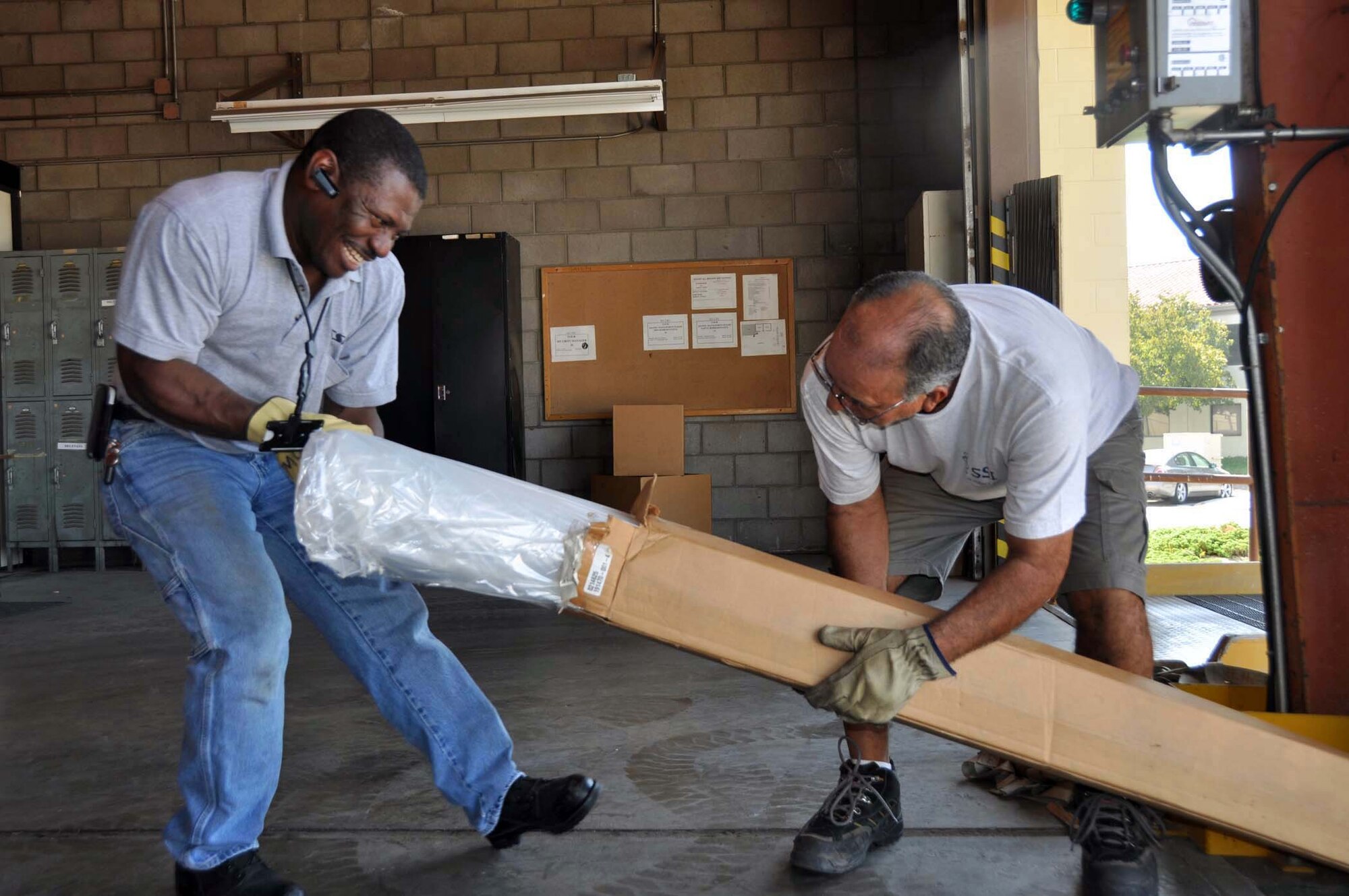 Willy Alexander and Rudy Trejo, Satellite Services, Inc., open a plastic pallet cover September 28, 2011, to prepare pallets of humanitarian supplies  for shipment to Kabul, Afghanistan.  The 24 skids of humanitarian supplies that arrived at March Air Reserve Base from Women of Faith in Redlands were redistributed and secured onto pallets prior to their October 2nd departure on a 452nd Air Mobility Wing C-17 Globemaster III as part of the Denton Amendment, a U.S. government program that allows humanitarian cargo to be shipped free of charge via military aircraft on a space available basis.  (U.S. Air Force photo/Linda Welz)Amendment Program.  (U.S. Air Force photo/Linda Welz)